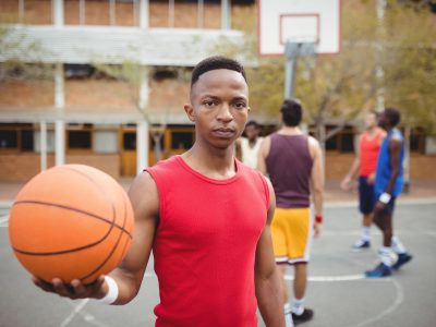 Male basketball player holding basketball in basketball court