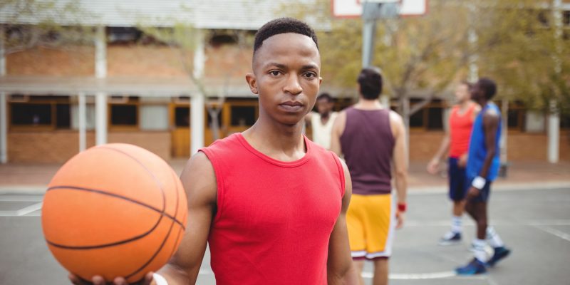 Male basketball player holding basketball in basketball court