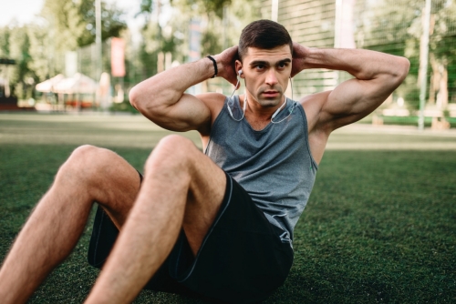 Male athlete doing exercises on the press outdoor